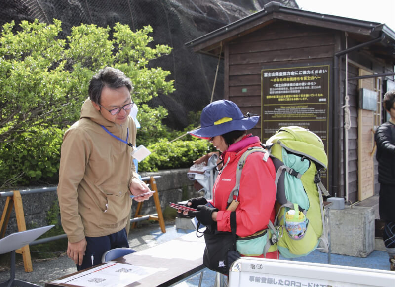 日本富士山的山梨縣側從今年7月1日登山季開始實施登山限制。圖為工作人員在五合目確認登山者是否有提前登記。（共同社）