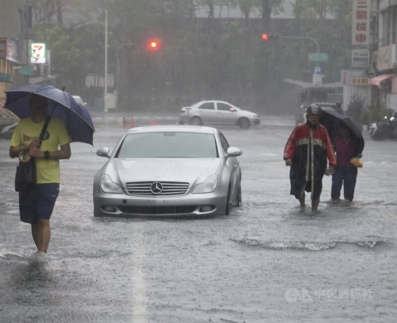 高雄市受颱風凱米影響，25日風雨持續，三民區三鳳宮一帶低窪處路面淹水，民眾撐傘涉水而過。中央社記者董俊志攝 113年7月25日