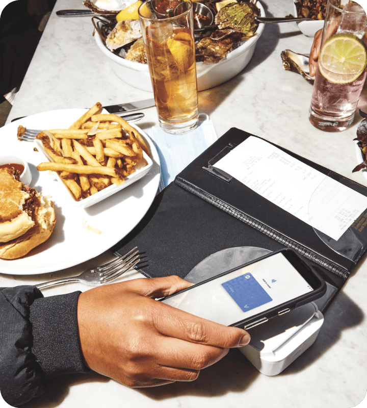 Half eaten hamburger and fries next to an open check at a restaurant