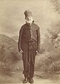 A studio photograph of Bill Thompson, a convict in Tasmania. He is wearing a convict uniform and leg irons. Dated: 1870s.