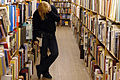 A woman browses a bookshelf