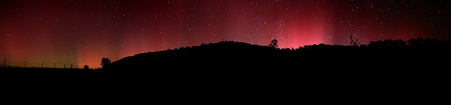 Deutsch: Kommt starke Aurora in niedrigeren Breiten über den Horizont, zeigt sie dort primär ihre hohen, roten Teile. English: The tops of aurorae are visible over the horizon in lower latitudes.