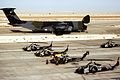 Four AH-1Ws and a UH-1N are parked on the flight line in front of a C-5A Galaxy during Operation Desert Shield