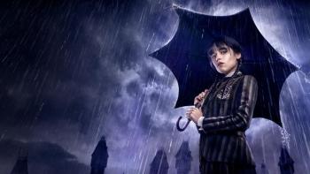 Wednesday Addams character stands with umbrella 