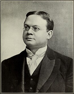 Portrait en noir et blanc d'un homme portant des lunettes et regardant vers la gauche du cliché.