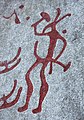 Nordijski bronastodobni petroglif s postavo, ki drži kladivu podoben predmet, med tanumskimi vklesanimi skalami, Švedska