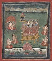 Depicted enthroned, a decapitated, dark-complexioned woman wearing a red/orange sari holds a sword in her left hand and her own severed head (with a lotus crown) on a platter in her right hand. Five seated devotees (including one with a ram's head) with folded hands surround her. A lake with a large lotus is in the foreground.