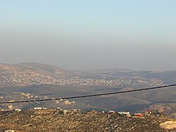 In the front, beneath the telephone cable, is mount 725, an illegal Israeli outpost of Yitzhar. Beneath it, crossed by the telephone cable, is Einabus. Covering most of the farther area is the municipality of Qabalan. Behind the right side of Qabalan is Talfit, and behind it is Qaryut. Behind the middle of Qabalan is Ahijah.