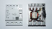 Geöffneter vierpoliger Fehlerstrom-Schutzschalter, Summenstromwandler mit rotbraunen, dicken Arbeitsstromwicklungen, der Sekundärwicklung zum Auslösemechanismus (gelb) und der Teststrom-Wicklung (blau)