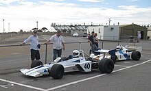 A mid-engined single-seater racing car with large aerodynamic wings