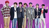 BTS on a red carpet with a purple background