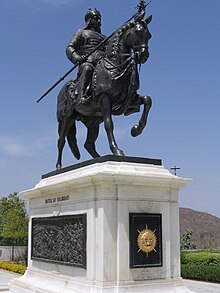 Statue équestre représentant un homme en uniforme, une lance à la main, sur un cheval bridé.