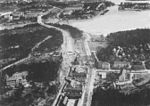 Vy över nuvarande Alviksplan (foto 1933) och uppfarten till Tranebergsbron. Bromma-Teatern, Brommabiografen, står kvar ännu idag, men nödbostäderna är revs 1942.