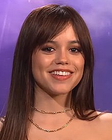 Jenna Ortega smiling against a purple background