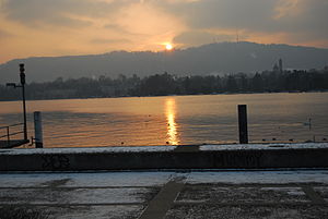 Uetliberg, hejmmonto de Zuriko, sunsubiro ĉe la duonfrostiĝinta Lago de Zuriko en feburaro 2012