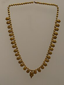Photographe d'un collier composé de miniatures de tortue en or.