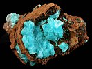 In a vug of limonite are intergrown clusters of rhombohedral calcite with inclusions of fibrous aurichalcite