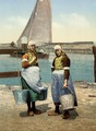 Twee dames in traditionele klederdracht op het eiland Marken, die emmers met water dragen met behulp van een juk (circa 1900)