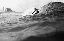 Black and white photo of surfer riding small wave