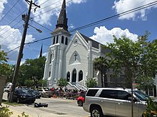 A large crowd of people gathered in front of a white-painted church