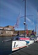 Vu de l'avant, voilier blanc, recouvert d'un drapeau néerlandais, amarré au ponton.