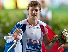 Lemaitre, avec le drapeau français sur les épaules, et un bouquet de vainqueur dans la main gauche.