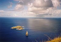 A sea view form high on a cliff, three islands are visible, two low and the third a spire of rock