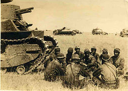 Photo en noir et blanc d'hommes assis auprès de chars de combat.