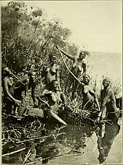 Photo noir et blanc de femmes noires nues, jouant et riant au bord d'un lac.