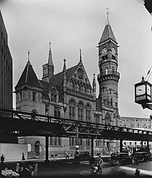 An elevated railroad partly covers the facade of an ornate building