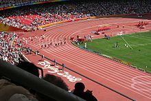 Le stade d'athlétisme de Pékin avec des gradins bondés et des athlètes sur la piste lors des Jeux olympiques d'été de 2008.