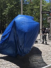 Charging Bull covered in a blue tarp and surrounded by barricades to protect it from vandalism. This photo was taken in June 2020, during the George Floyd protests in New York City.