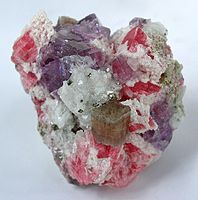 Kristal apatit terletak di depan dan tengah pada rombo rhodochroite berwarna ceri merah, batu fluorit berwarna ungu, kuarsa dan serbuk dari batu pirit kuningan-berwarna kuning.