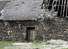 Photographie d'une maison en ruine montrant l'appareil de schiste typique de la région.