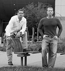 Black and white photograph of two men standing in front of an office building.