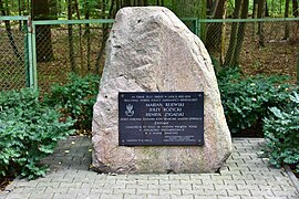 Photographie d'une plaque commémorative accrochée sur un bloc de roche.