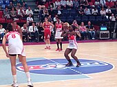 Une femme en habit de sport se prépare à lancer une balle.