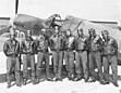 8 Tuskegee Airmen posent devant un chasseur Curtiss P-40 (Afrique du Nord, 1943).