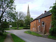 red brick building in the foreground with church and spire in the background