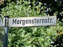 Straßenschild vor einem Laubbaum