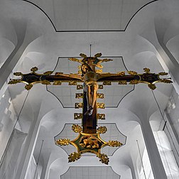 Cruz triunfal na igreja evangélica de São Nicolau, Kiel, Alemanha. É uma cruz ou crucifixo, especialmente grande colocado acima da entrada da capela-mor de uma igreja medieval. Alternativamente, é uma grande escultura ou pintura da crucificação de Jesus. O termo “cruz triunfal”, que é mais comum na Europa, significa o triunfo que o ressuscitado Jesus Cristo (Christus triunfans) conquistou sobre a morte. (definição 5 224 × 5 224)