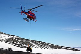 Am Hubschrauberlandeplatz: Ein Hubschrauber trägt ein ATV als Außenlast auf die Black Island