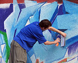 Un artist realizând un graffiti în București.
