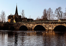 Bro över Helge å i Broby med Östra Broby kyrka i bakgrunden.