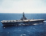 Medium-size aircraft carrier with numerous aircraft on its flight deck.