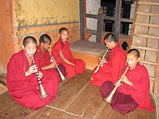 Szerzetesfiúk lingm-en (ajaksípos hangszer) játszanak