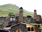 Stone houses with several towers, hill in the background