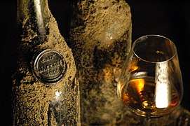 Photographie de bouteilles de vin et d’un verre.