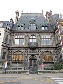 Photographie en couleurs. Maison bourgeoise à la façade finement ouvragée. Ciel dégagé.