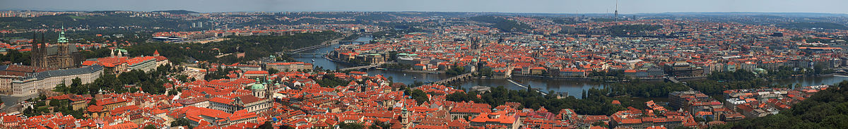 Panorama Prahy z Petřínské rozhledny. Vlevo jsou vidět Hradčany s Pražským hradem, jemuž dominuje svatovítská katedrála, pod nimi se rozkládá Malá Strana s chrámem sv. Mikuláše a věží Pražského Jezulátka. Ve středu snímku záhyb Vltavy překlenutý (zprava) Karlovým, Mánesovým a Čechovým mostem obtéká Staré Město. U horizontu leží Severní Město, Letná a Holešovice, Karlín, Vinohrady, Nové Město, Žižkov, Pankrác, Podolí i další čtvrti a Žižkovský vysílač.